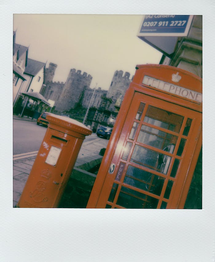 pexels-photo-3704052 Classic red telephone booth with Conwy Castle in the background, capturing nostalgia in Wales, UK.